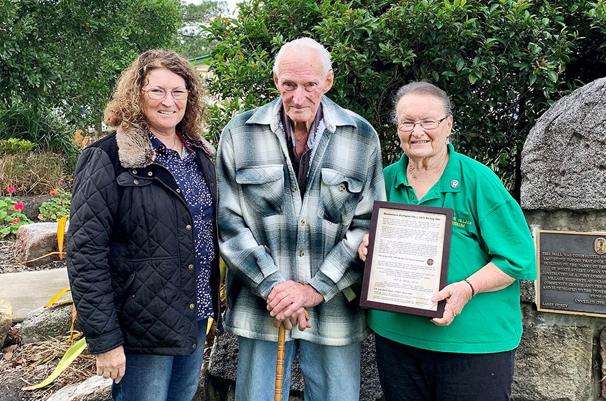 Julie McDonald with her father Lee Wendt presenting framed story to Coralyn Cowin from Logan Village Museum